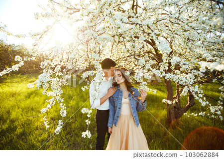 Beautiful loving couple in blooming gardens. Wedding concept. Great sunset light. Lovely newlyweds. 103062884