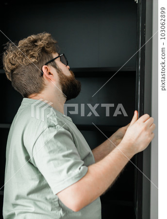 Young attractive man assembles furniture - handwerker and interior objects concept 103062899
