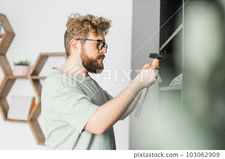 Portrait of man assembling furniture. Do it yourself furniture assembly at home Portrait of man assembling furniture. Do it yourself furniture assembly at home 103062909