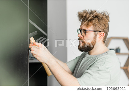 Portrait of man assembling furniture. Do it yourself furniture assembly at home Portrait of man assembling furniture. Do it yourself furniture assembly at home 103062911