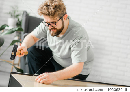 Portrait of man assembling furniture. Do it yourself furniture assembly at home Portrait of man assembling furniture. Do it yourself furniture assembly at home 103062946