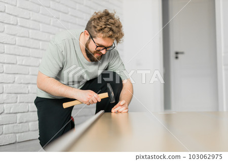 Young attractive man assembles furniture - handwerker and interior objects concept Young attractive man assembles furniture - handwerker and interior objects concept 103062975
