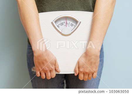 Young woman holding white scales to check the results of her diet 103063050