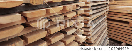 Stacked wooden boards in the woodworking industry. Stacks with pine lumber. Folded edged board. Wood harvesting workshop. Narrow banner. Stacked wooden boards in the woodworking industry. Stacks with pine lumber. Folded edged board. Wood harvesting workshop. Narrow banner. 103064619