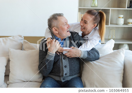 Happy family. Caring grown up daughter hugging loving older man father. Young woman embracing dad grandfather enjoying sweet bonding. Family generations together at home. Family moment love and care Happy family. Caring grown up daughter hugging loving older man father. Young woman embracing dad grandfather enjoying sweet bonding. Family generations together at home. Family moment love and care 103064955