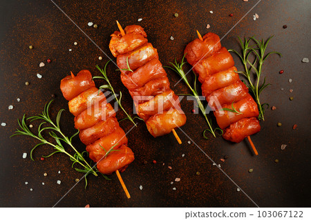 Fresh raw marinated skinless chicken leg meat skewers with fresh herbs on a black background.Top view.Copy space.Closeup of chicken meat.Procurement for designers. Fresh raw marinated skinless chicken leg meat skewers with fresh herbs on a black background.Top view.Copy space.Closeup of chicken meat.Procurement for designers. 103067122