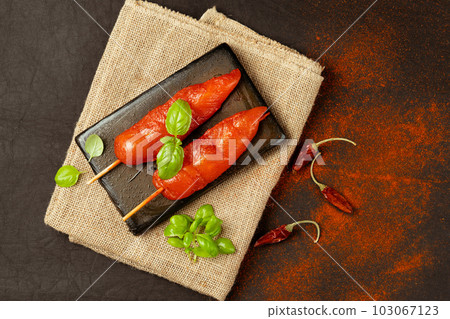 Chicken fillet inner skewers.Food concept.Food for retail.Ogranic food,healthy eating.Fresh raw marinated chicken meat skewers iner fillet with fresh herbs on a black background.Top view. 103067123