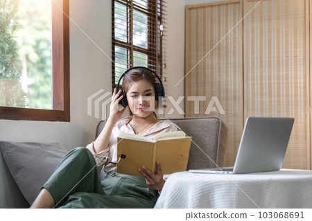 Attractive young Asian woman in the minimal and comfortable living room enjoying reading a book 103068691