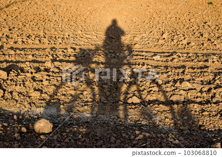 Shadow of a cyclist with a bicycle on a plowed field Shadow of a cyclist with a bicycle on a plowed field 103068810