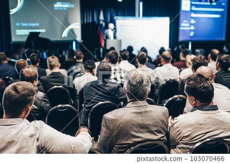 Speaker giving a talk in conference hall at business event. Rear view of unrecognizable people in audience at the conference hall. Business and entrepreneurship concept 103070466