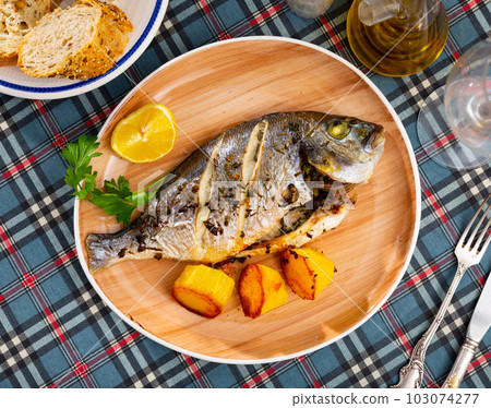 Dorado fish with lemon and potatoes served at plate close up Dorado fish with lemon and potatoes served at plate close up 103074277
