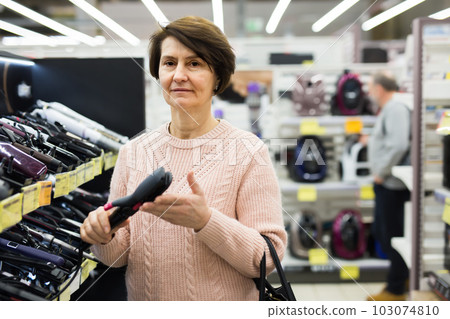 Portrait of a European woman choosing an electric styler Portrait of a European woman choosing an electric styler 103074810
