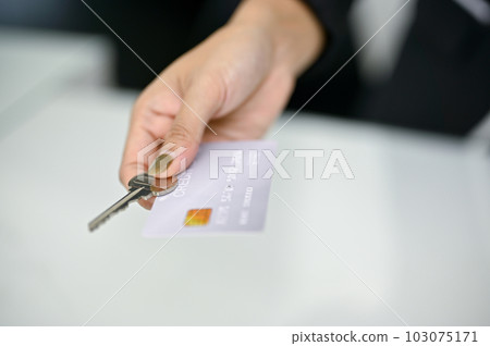 Close-up image of a receptionist giving a credit card and a room key to a customer 103075171