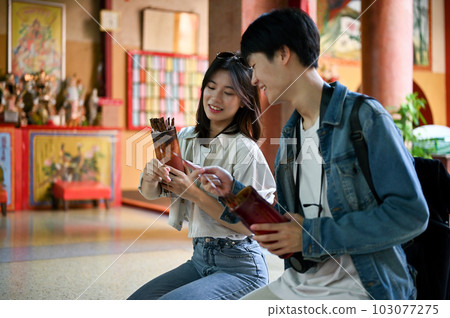 An Asian tourist couple prays for good luck and shakes Chinese fortune sticks An Asian tourist couple prays for good luck and shakes Chinese fortune sticks 103077275