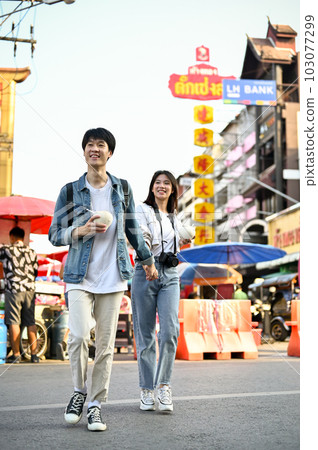 A tourist couple holding hands while crossing the street, enjoys sightseeing A tourist couple holding hands while crossing the street, enjoys sightseeing 103077299