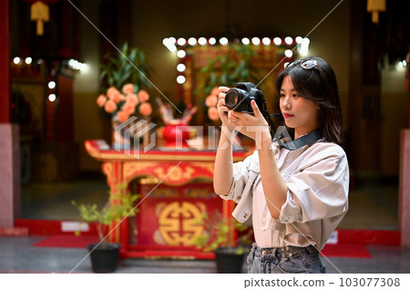 A female tourist visiting and taking photos of a beautiful Chinese temple. 103077308