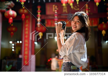 A female tourist enjoying her historical sightseeing in the old town, taking photos 103077314