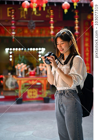 A female tourist checking photos on her camera, visiting a Chinese temple in the old town 103077319