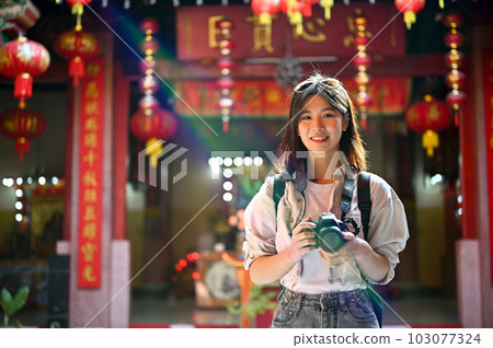 A female tourist holding her camera, sightseeing and visiting a beautiful Chinese temple. A female tourist holding her camera, sightseeing and visiting a beautiful Chinese temple. 103077324