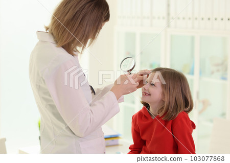Optometrist examining little girl eye in doctor premise Optometrist examining little girl eye in doctor premise 103077868