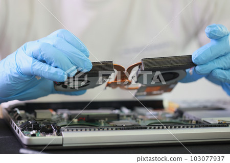 Male master in gloves holds cooling system of broken laptop 103077937