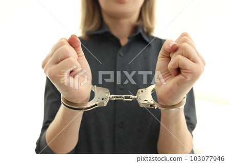 Female person with handcuffs on wrists in prison cell Female person with handcuffs on wrists in prison cell 103077946