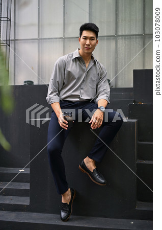 A businessman sits outside with his takeaway coffee cup. 103078009