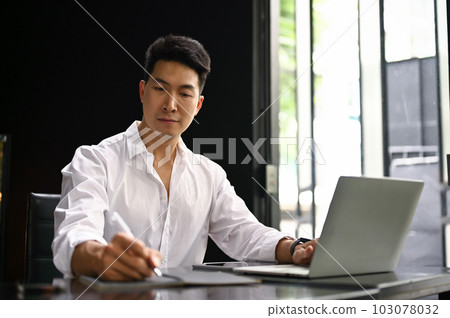 Focused Asian businessman working on his business project at his desk in the office. Focused Asian businessman working on his business project at his desk in the office. 103078032
