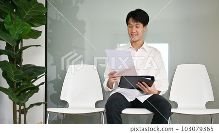 Smart Asian male candidate sits in a waiting room, waiting for a job interview. 103079365