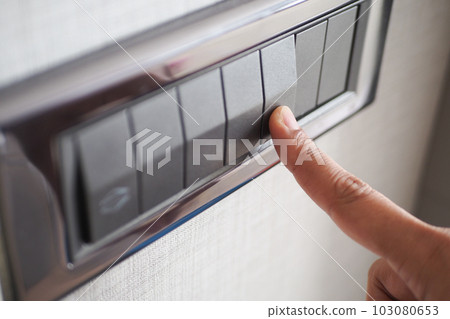 A finger turning on lighting switch . 103080653