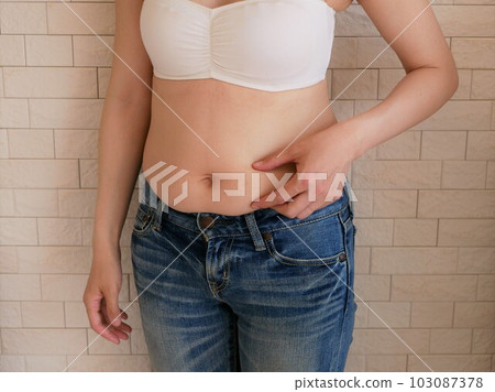 A young woman who is worried about her stomach 103087378