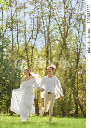 Happy newlyweds holding hands and running across the lawn Happy newlyweds holding hands and running across the lawn 103088331
