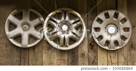 Old wheel rims from different cars on the wall, like a design on the street 103088864