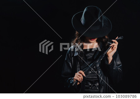 Sexy female dominant mistress with a whip for BDSM sex with submission and domination in a leather raincoat 103089786
