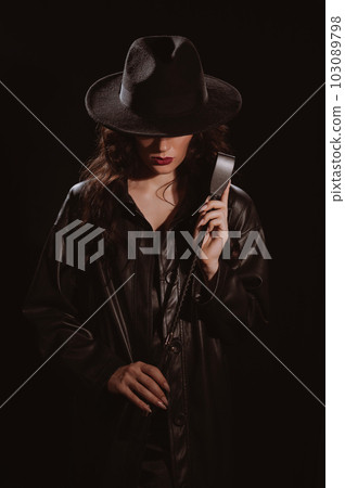 woman in a leather raincoat and hat with a whip flogger for BDSM woman in a leather raincoat and hat with a whip flogger for BDSM 103089798