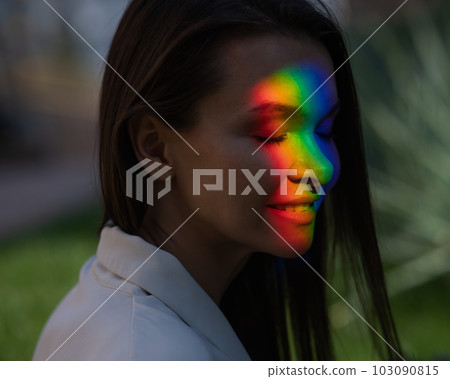Portrait of caucasian woman with rainbow beam on her face outdoors. Portrait of caucasian woman with rainbow beam on her face outdoors. 103090815