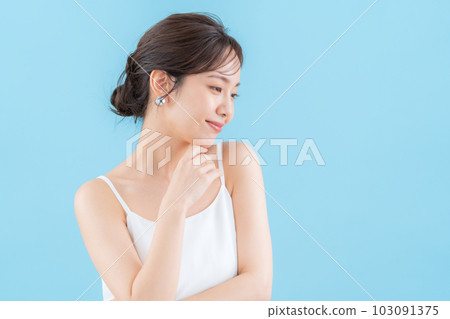 Young woman doing skin care on blue back 103091375