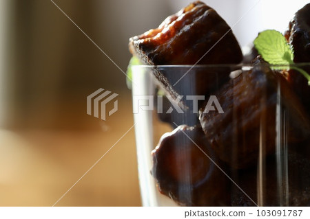 Mini canelés in a glass with mint leaves Mini canelés in a glass with mint leaves 103091787