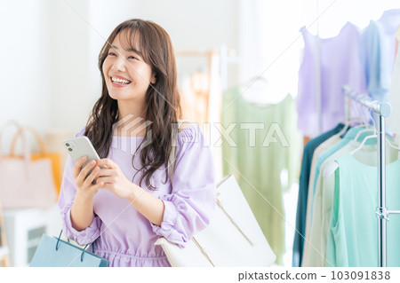 Young woman operating a smartphone while shopping at a store 103091838