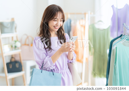 Young woman operating a smartphone while shopping at a store Young woman operating a smartphone while shopping at a store 103091844