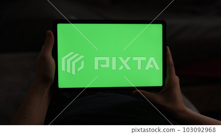 Man at home lying on a couch with tablet pc with green screen Man at home lying on a couch with tablet pc with green screen 103092968