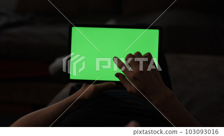 Man at home lying on a couch with tablet pc with green screen Man at home lying on a couch with tablet pc with green screen 103093016