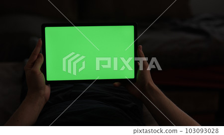 Man at home lying on a couch with tablet pc with green screen Man at home lying on a couch with tablet pc with green screen 103093028
