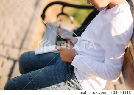 Teenage boy in white shirt use powerbank for charging his smartphone otside. Low battery on smartphone Teenage boy in white shirt use powerbank for charging his smartphone otside. Low battery on smartphone 103093318
