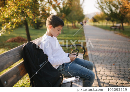 Teenage boy in white shirt use powerbank for charging his smartphone otside. Low battery on smartphone 103093319