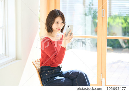 便衣的年輕女人，客廳，智能手機 103093477