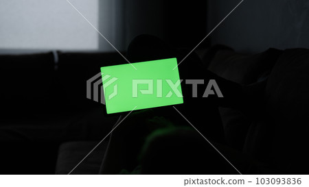 Man at home lying on a couch with tablet pc with green screen Man at home lying on a couch with tablet pc with green screen 103093836