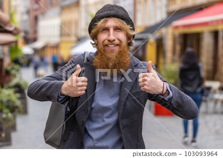 Young man showing thumbs up, like sign positive something good positive feedback in city street 103093964