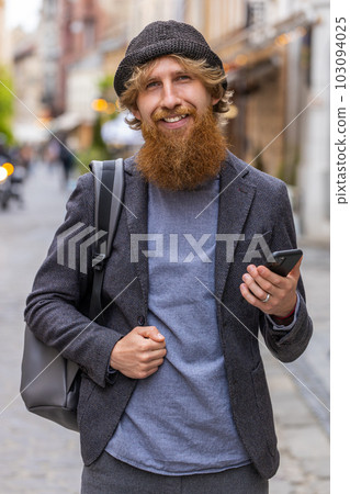 Young man use smartphone typing text messages browsing internet finishing work looking at camera 103094025