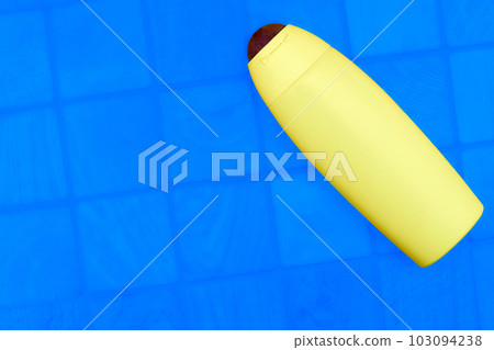 Yellow plastic bottle for detergents and shampoos on a checker blue background 103094238